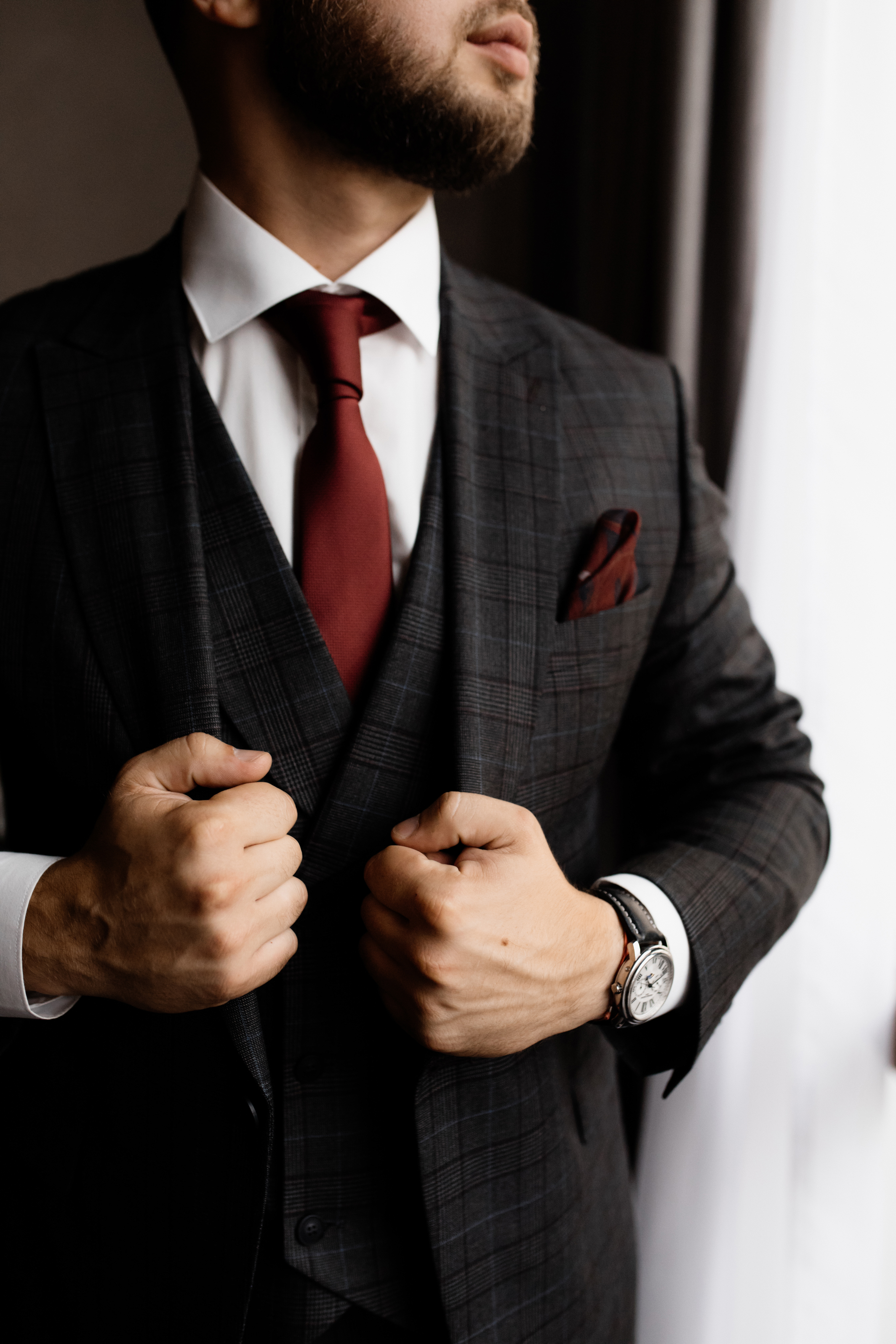 Bearded man in stylish tuxedo and red tie, strong man’s hands